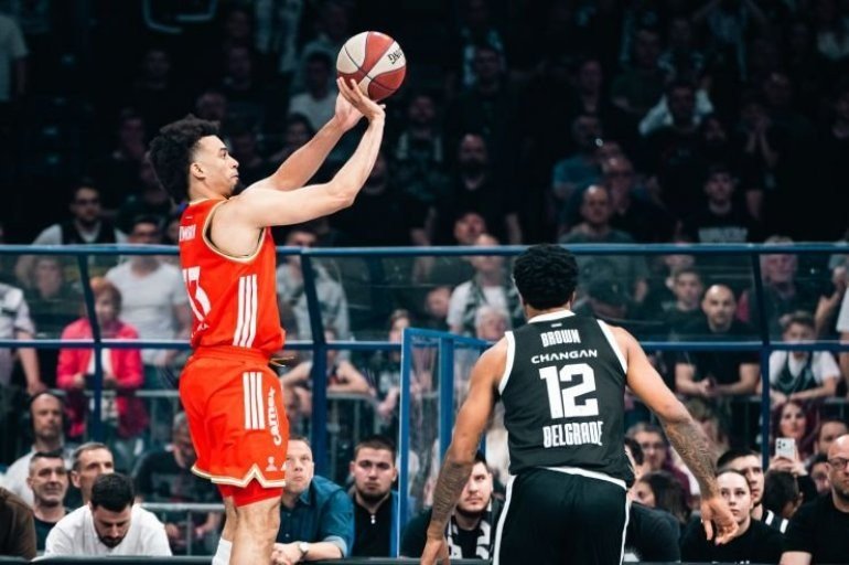 Игрок Црвены Звезды выполняет бросок в прыжке через руку защитника Партизана Стерлинга Брауна (№12) во время дерби АБА-лиги