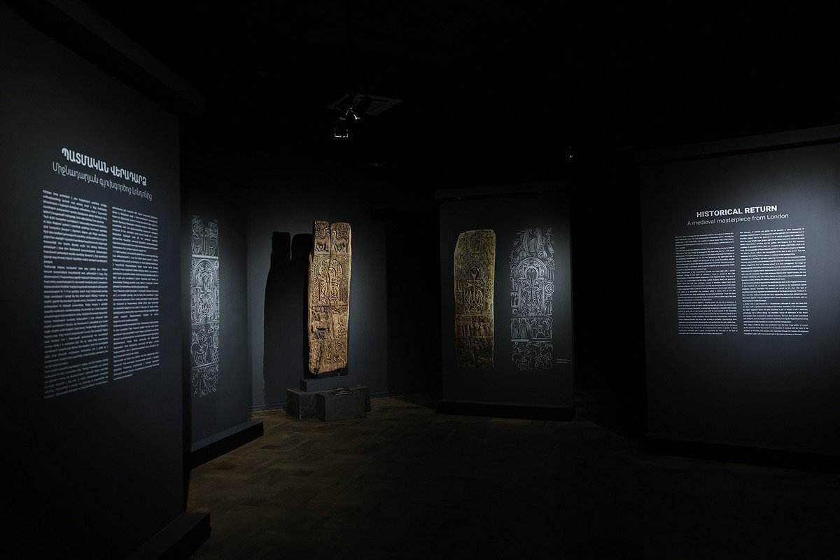 Общий вид выставочного пространства с деревянной панелью и её проекцией, рядом — двуязычные информационные стенды с заголовком «Историческое возвращение» на армянском и английском языках
