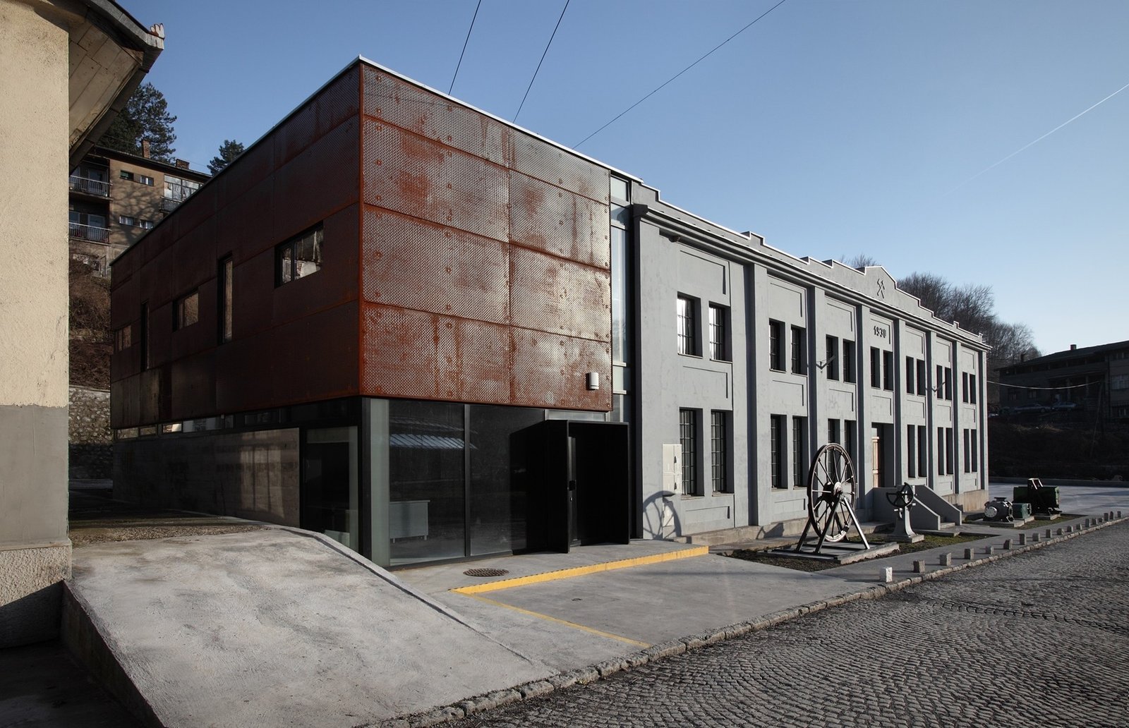 Современное промышленное здание с фасадом из кортена, состыкованное со старой каменной постройкой