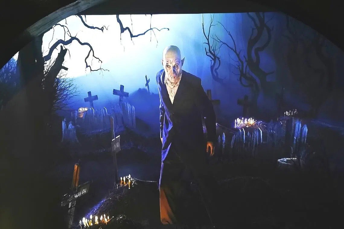 Инсталляция с фигурой графа Дракулы среди крестов и свечей в синем освещении