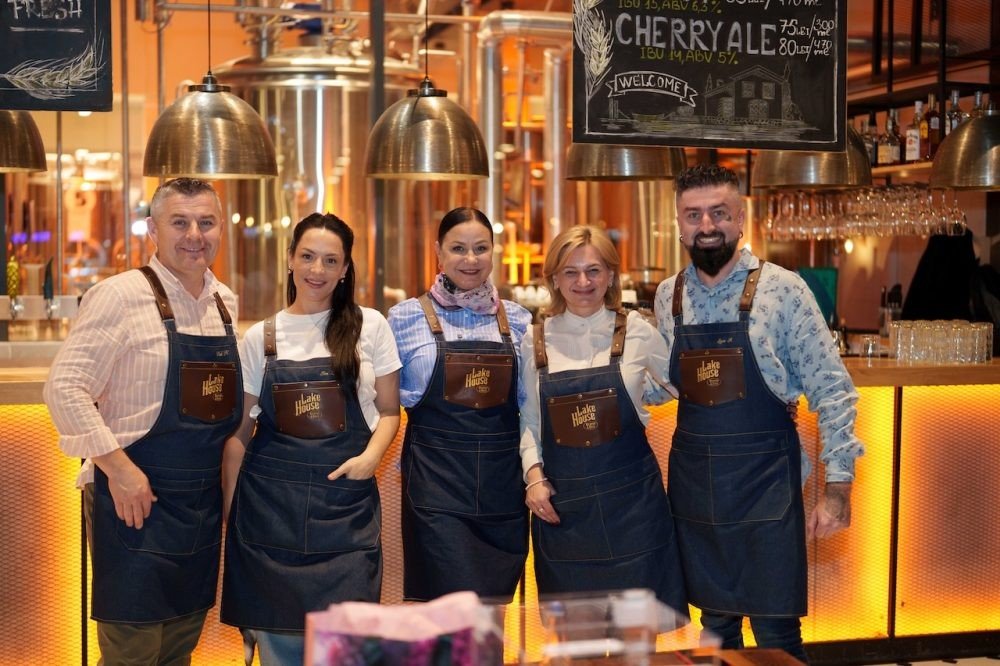 Звёзды Молдовы наденут фартуки ради 150 семей к Пасхе Пятеро волонтёров-официантов в одинаковых фартуках за барной стойкой ресторана Lake House Brewery