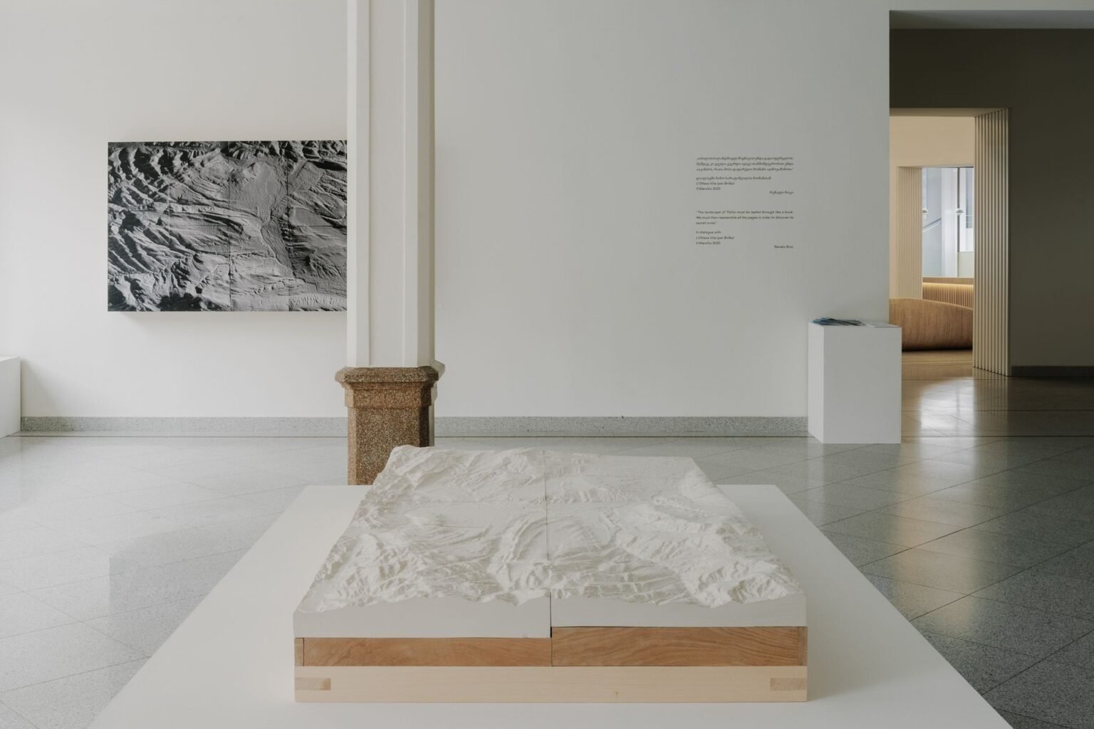 Тбилиси из гипса: 100 человек создали рельефную карту города Зал TBC Concept Gallery в Тбилиси с гипсовой моделью рельефа Тбилиси на деревянном постаменте и чёрно-белой фотографией ландшафта на стене