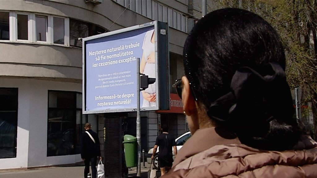 Антикесаревы билборды в Бухаресте: врачи назвали их антинаучными Женщина фотографирует антикесарев билборд на улице Бухареста
