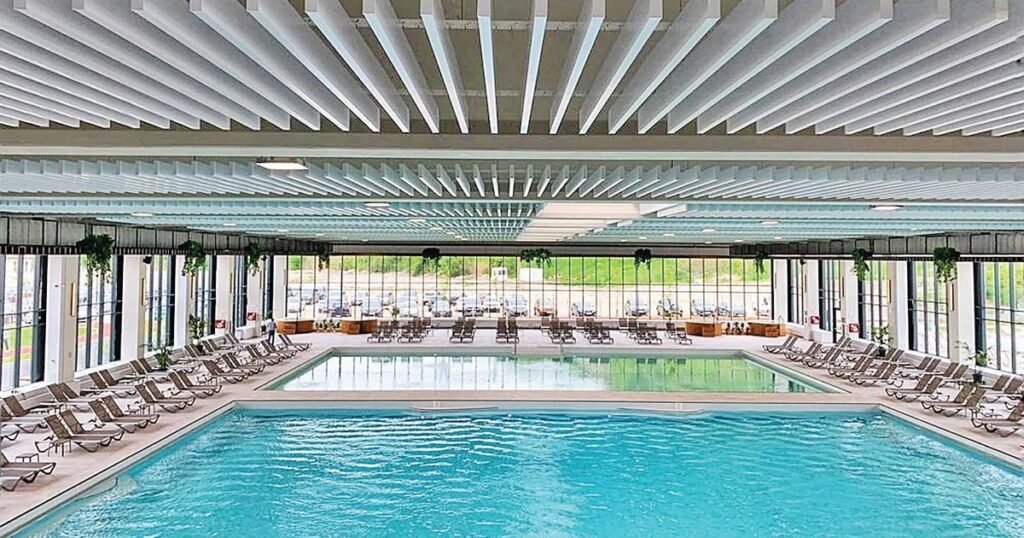 114 000 путёвок на бальнеолечение для пенсионеров Румынии Крытый бассейн современного бальнеологического комплекса с шезлонгами вдоль бортиков под ажурной крышей