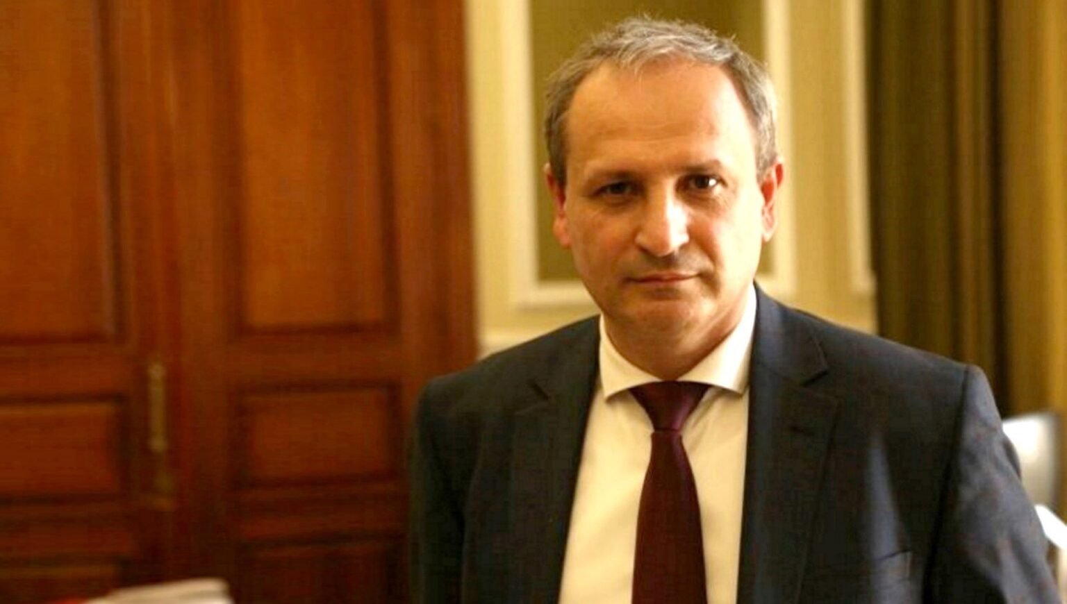 Виорел Бостан, доктор хабилитат и профессор УТМ, в официальном портретном кадре на фоне тёмных деревянных панелей кабинета