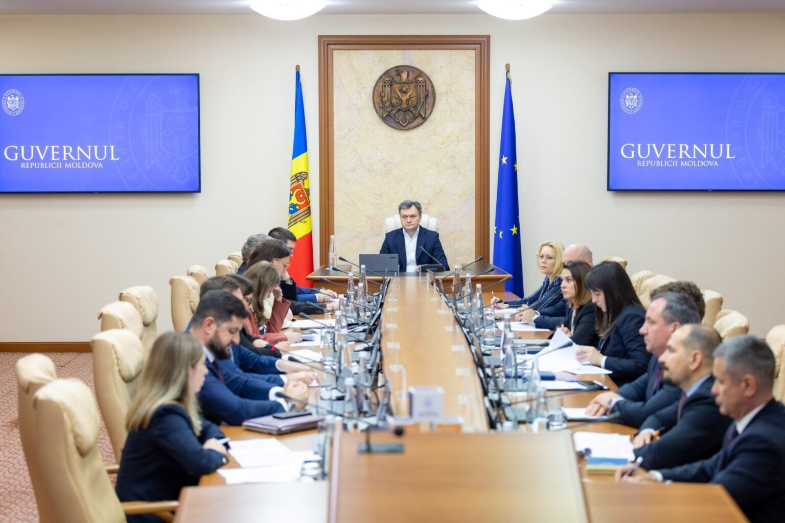 Заседание правительства Республики Молдова в Государственной канцелярии: премьер-министр и члены кабинета за длинным столом под государственным гербом, флагами Молдовы и ЕС