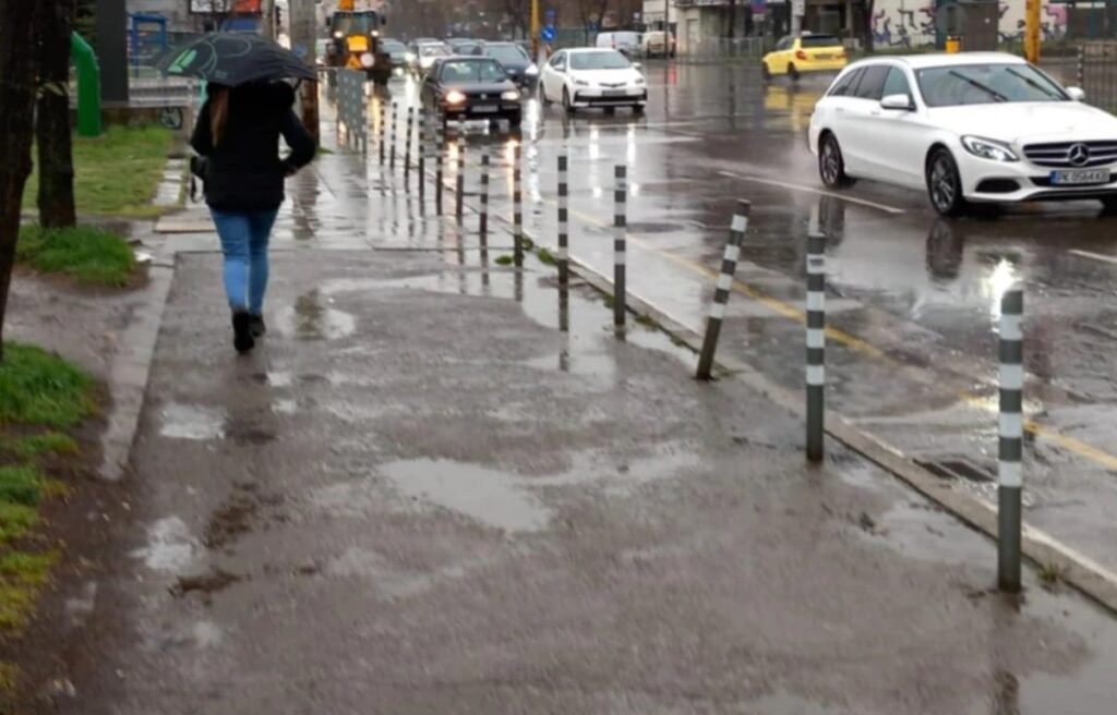 Пешеход с зонтом на мокрой улице Софии во время сильного дождя