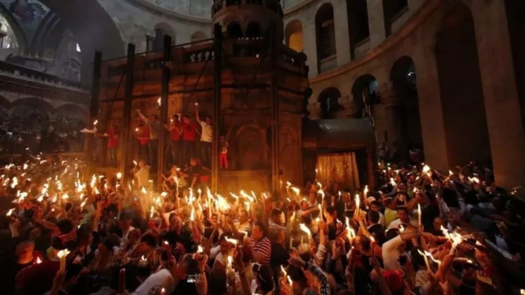 Толпа верующих с горящими свечами и факелами внутри Храма Гроба Господня во время церемонии схождения Благодатного огня