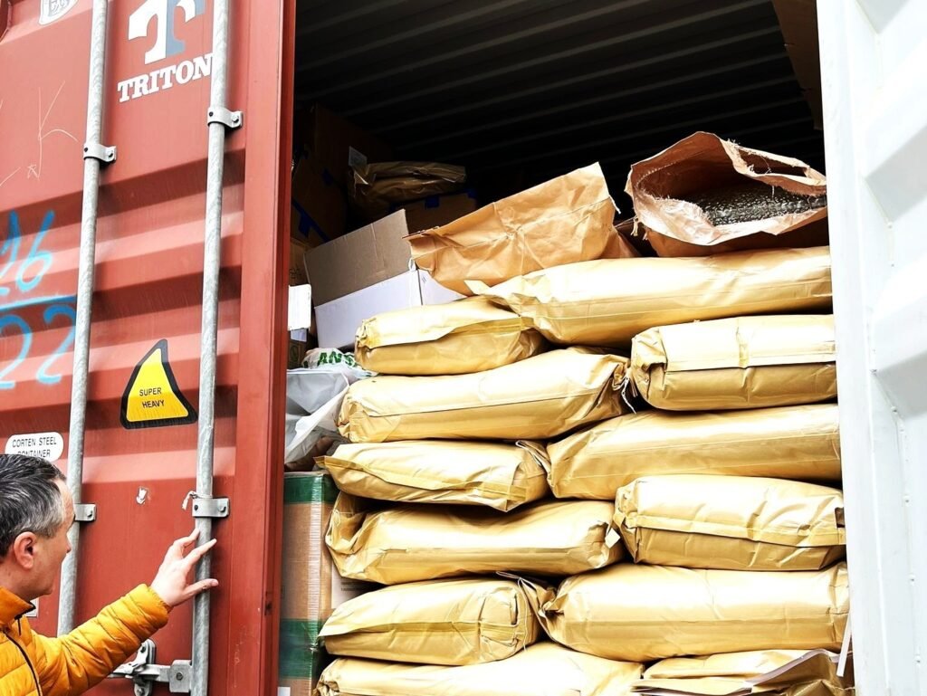 Инспектор проверяет мешки с семенами тыквы, уложенные в транспортном контейнере на границе Молдовы