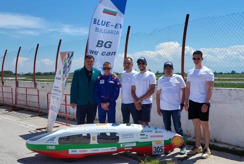 Команда учеников из Чепеларе рядом с электромобилем в цветах болгарского флага на треке