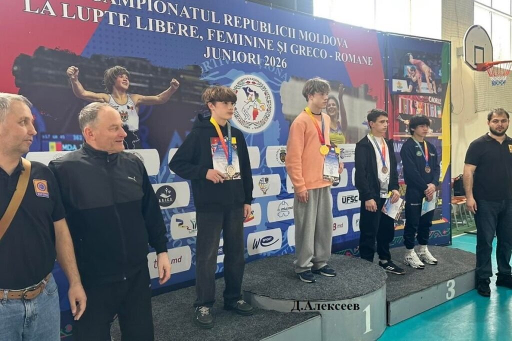 Церемония награждения на чемпионате Молдовы по борьбе среди юниоров до 15 лет. Спортсмены стоят на пьедестале почёта с медалями и дипломами на фоне баннера чемпионата