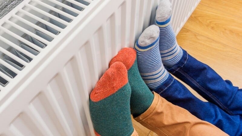 Ноги в разноцветных носках греются у домашнего радиатора отопления