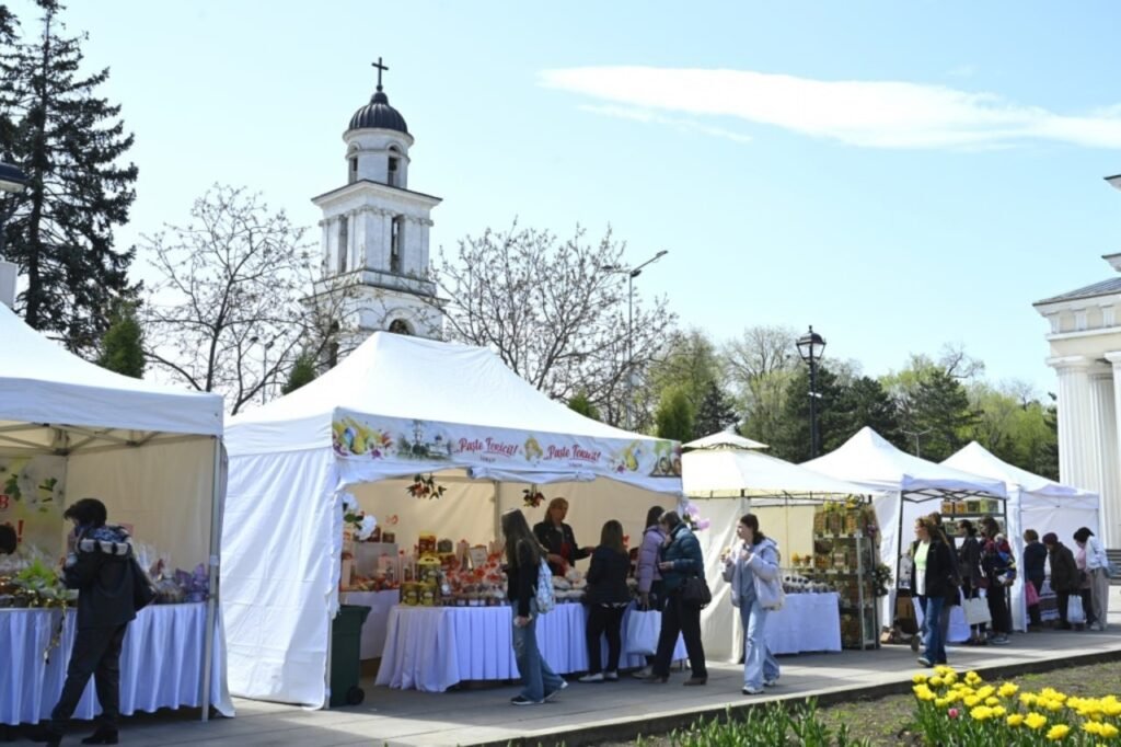 Палатки пасхальной ярмарки у колокольни Кафедрального собора в Кишинёве, посетители выбирают свежие продукты и праздничные товары местных производителей