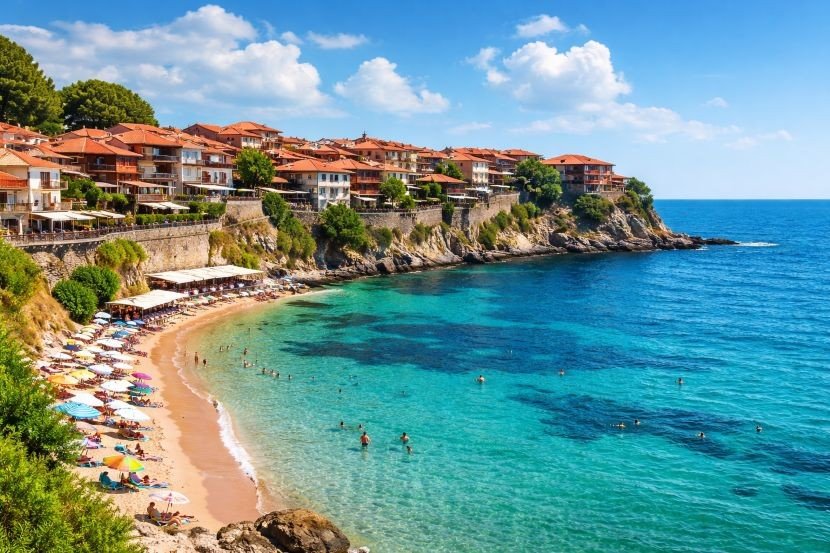 Панорамный вид на пляж Созополя с бирюзовой водой, белыми зонтиками на песке и старым городом на полуострове на фоне голубого неба с облаками