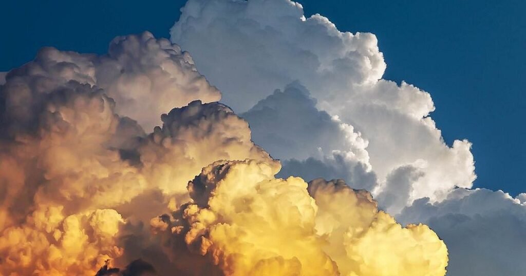 Мощные кучево-дождевые облака на фоне синего неба, золотистые и белые тона предвещают приближение атмосферного фронта