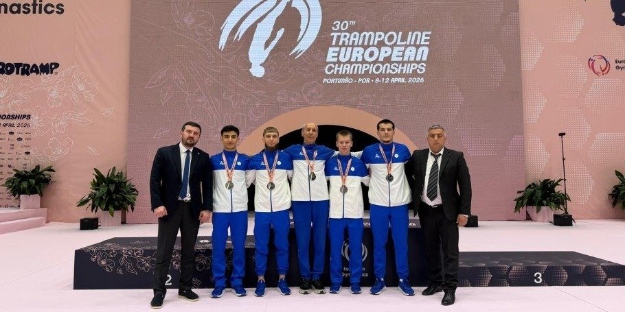 Сборная Азербайджана по тамблингу с серебряными медалями на фоне баннера 30-го чемпионата Европы в Портимане