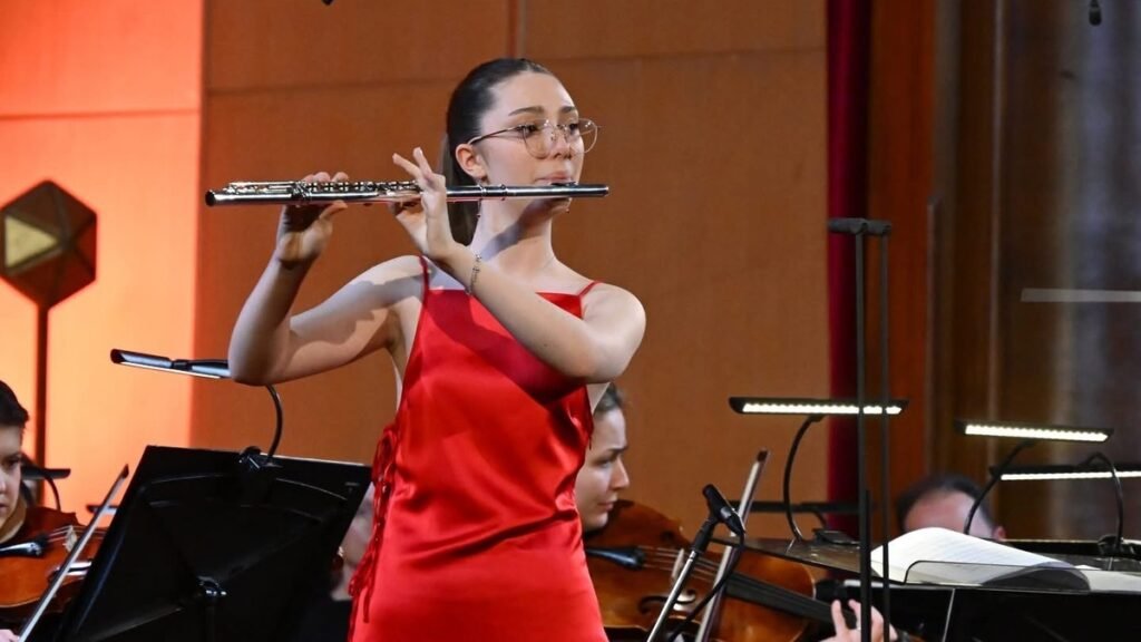 15-летняя флейтистка из Сербии покоряет мировую сцену Юная флейтистка Ива Вуянич выступает на сцене в красном платье в сопровождении оркестра