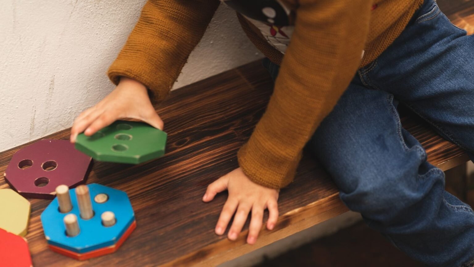 Аутизм в Молдове: эксперимент в парламенте и личные истории Ребёнок играет с разноцветными развивающими игрушками-сортерами на деревянной скамейке