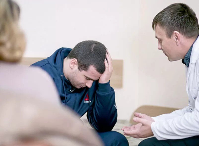 Врач-психиатр беседует с пациентом во время консультации в медицинском учреждении