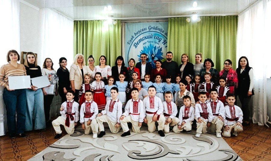 Групповое фото детей в национальных костюмах и взрослых в зале детского сада