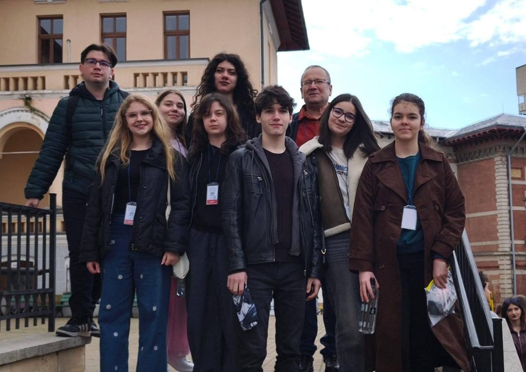 Группа учащихся и преподаватель позируют на фоне исторического здания после участия в Национальной олимпиаде по общественным наукам