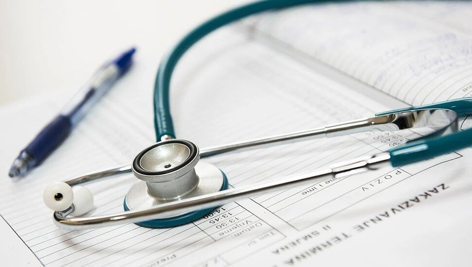 Стетоскоп на медицинских документах и бланках на планшете, рядом шариковая ручка