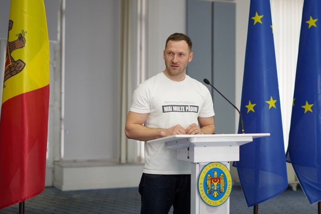 Представитель правительства Молдовы выступает на трибуне на фоне флагов Молдовы и ЕС
