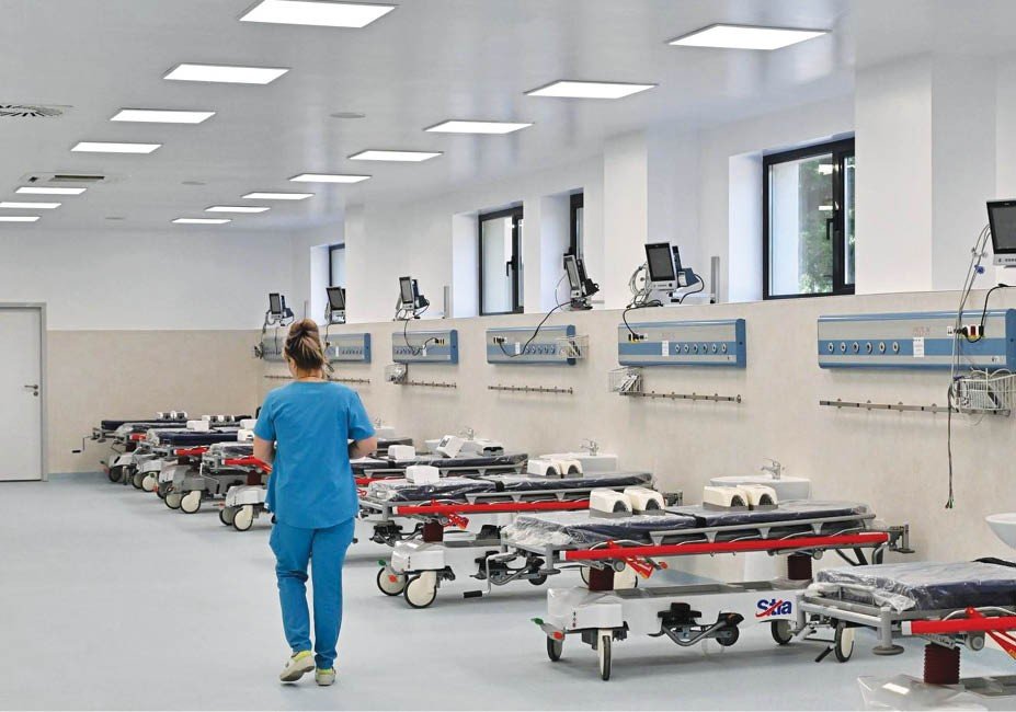 Медсестра идёт по палате скорой помощи больницы Плоешти, оборудованной каталками и медицинскими приборами