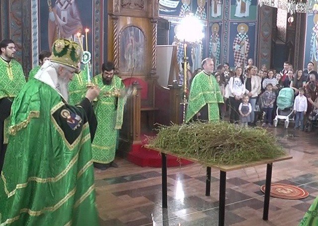 Священники в зелёных облачениях освящают вербные ветви во время церковной службы на Лазареву субботу (Врбицу), в храме присутствуют прихожане с детьми