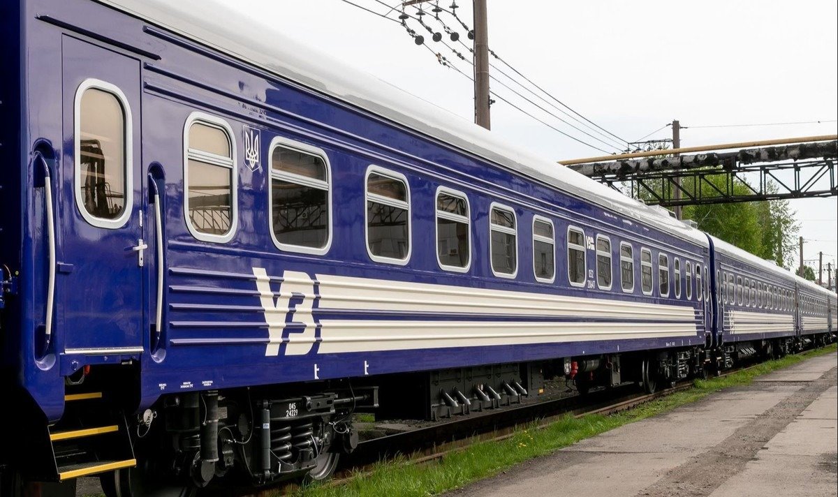 Синий пассажирский вагон Укрзалізниці с логотипом УЗ на путях