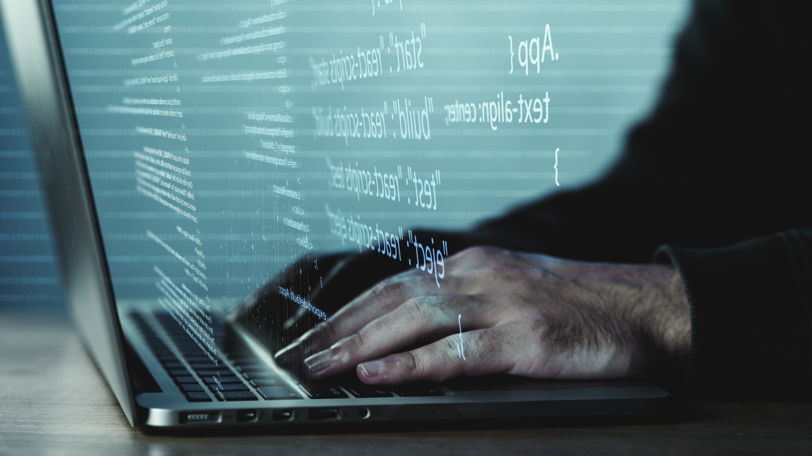 Программист работает за ноутбуком с кодом на экране