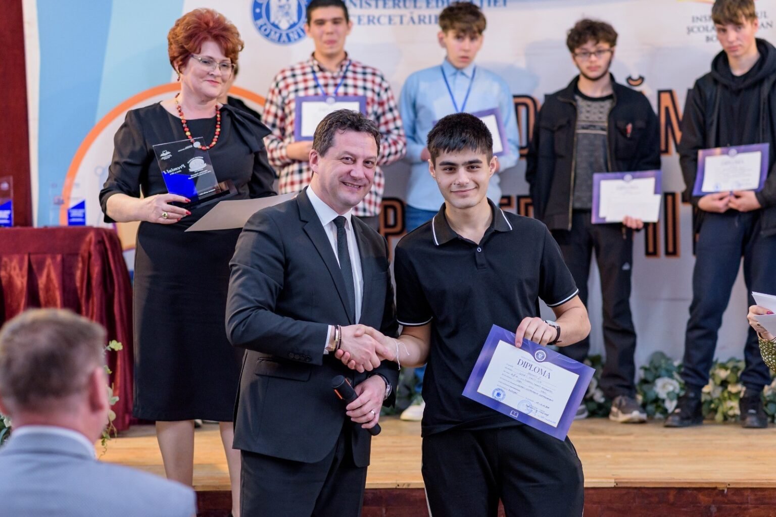 Школьники из Васлуя взяли 10 наград на олимпиаде по технологиям Церемония награждения на национальной олимпиаде по технологиям: официальное лицо пожимает руку ученику, держащему диплом, на сцене
