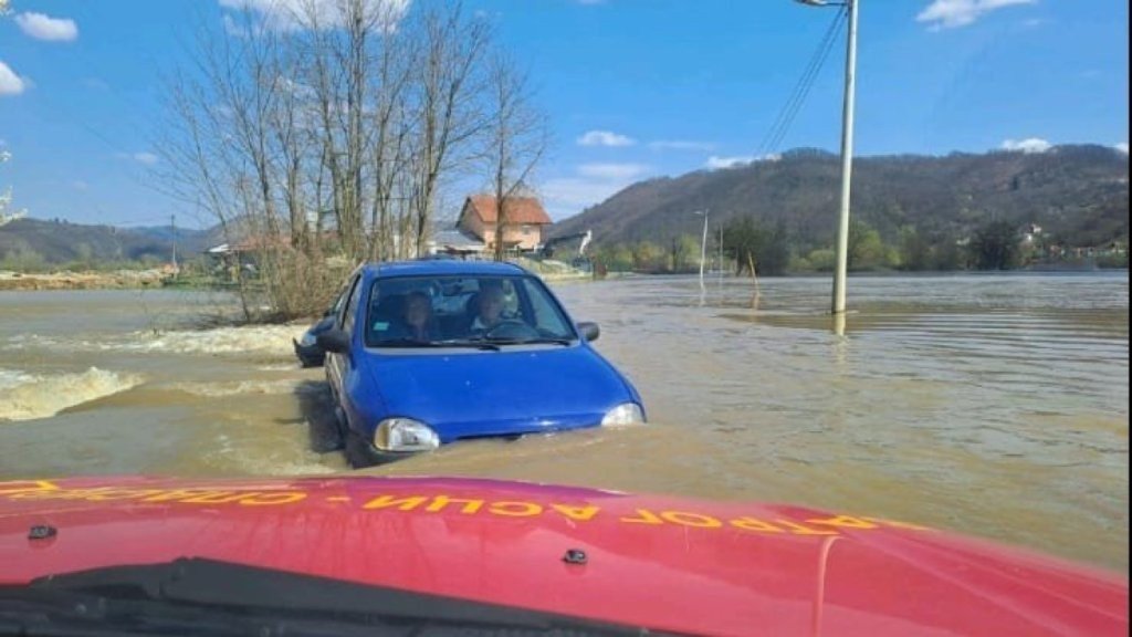 Паводок на Западной Мораве: пожилую пару спасли из потока Синий автомобиль в паводковой воде, впереди красный спасательный автомобиль