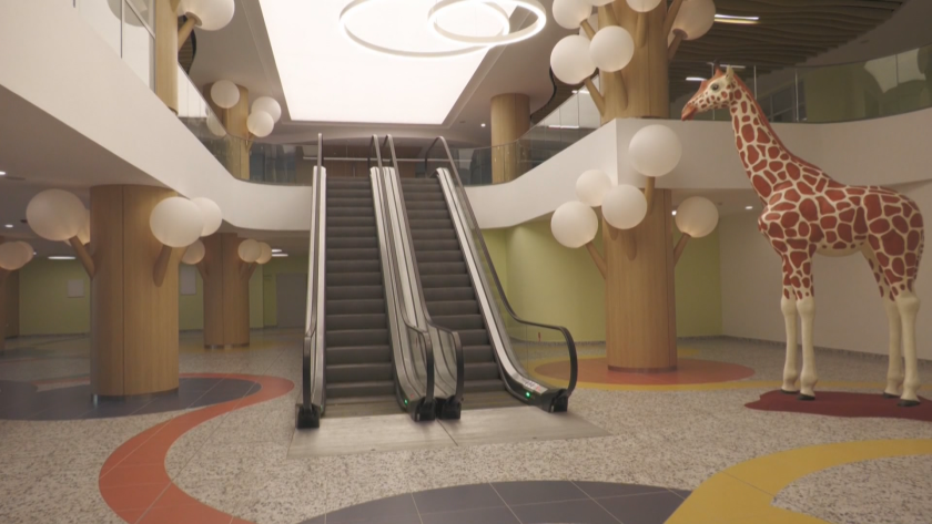 Просторное фойе детской больницы в Бургасе с эскалатором, декоративными деревьями и фигурой жирафа в натуральную величину