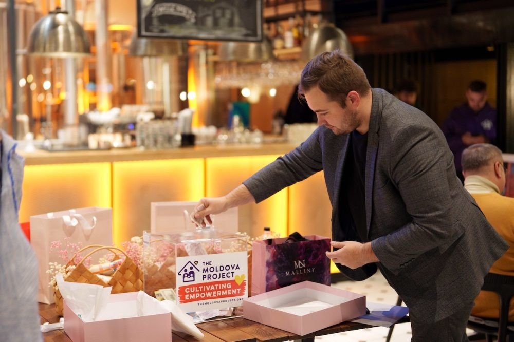 Мужчина готовит подарочные наборы на столе в ресторане во время благотворительного вечера