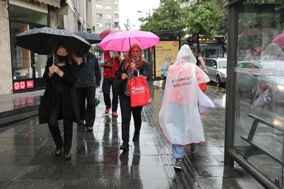 Люди с разноцветными зонтами на городской улице во время ливня