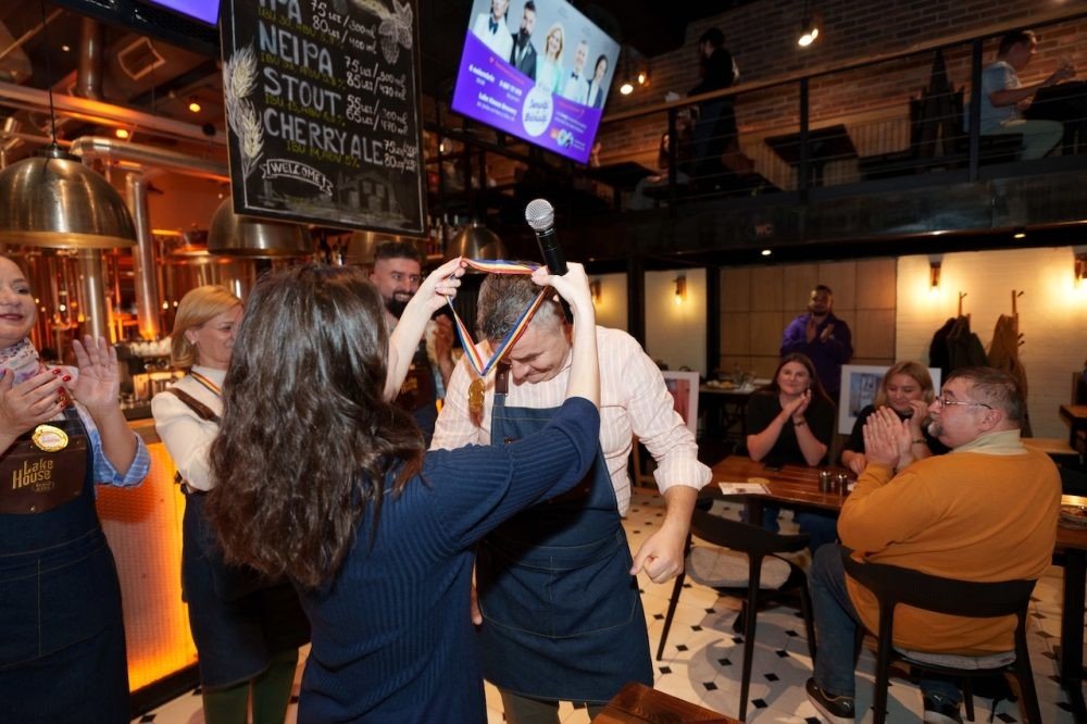 Гости аплодируют участнику в фартуке во время благотворительного вечера в ресторане