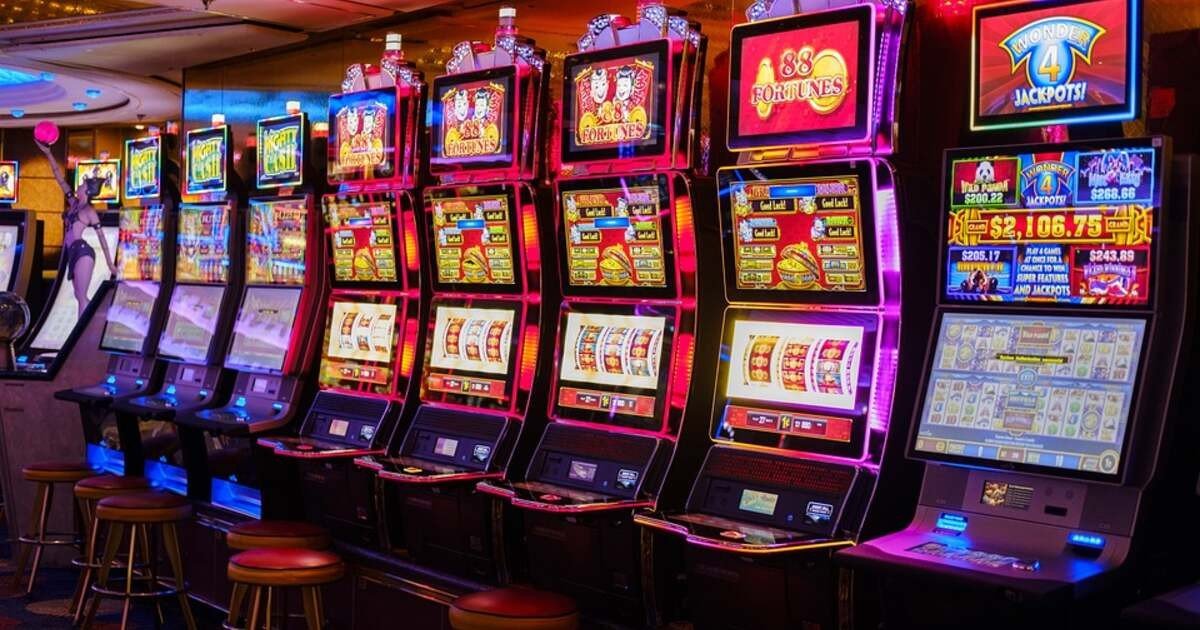 Ряд игровых автоматов с яркой подсветкой в зале азартных игр