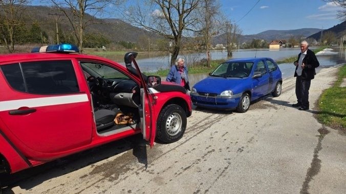 Пожилые люди у красного пожарного автомобиля и синего легкового автомобиля