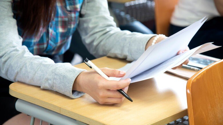 Ученица просматривает экзаменационные листы за партой в классе