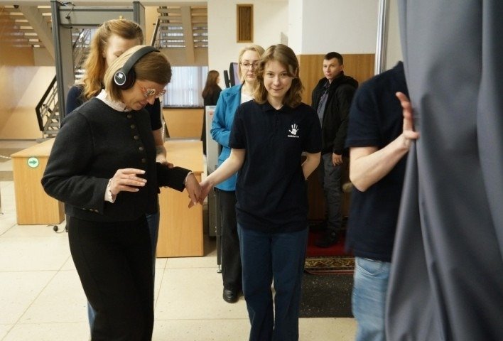 Участница в шумоподавляющих наушниках проходит сенсорный эксперимент, моделирующий восприятие людей с аутизмом, на мероприятии Министерства образования