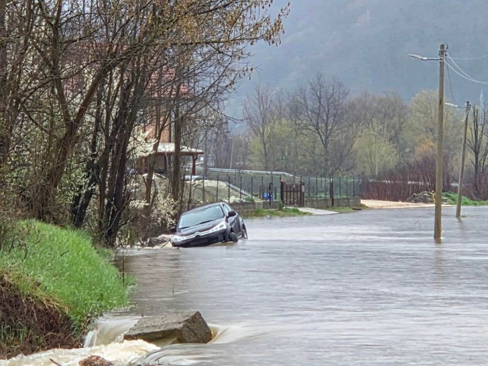 Автомобиль наполовину затоплен на дороге, холмы и забор на фоне