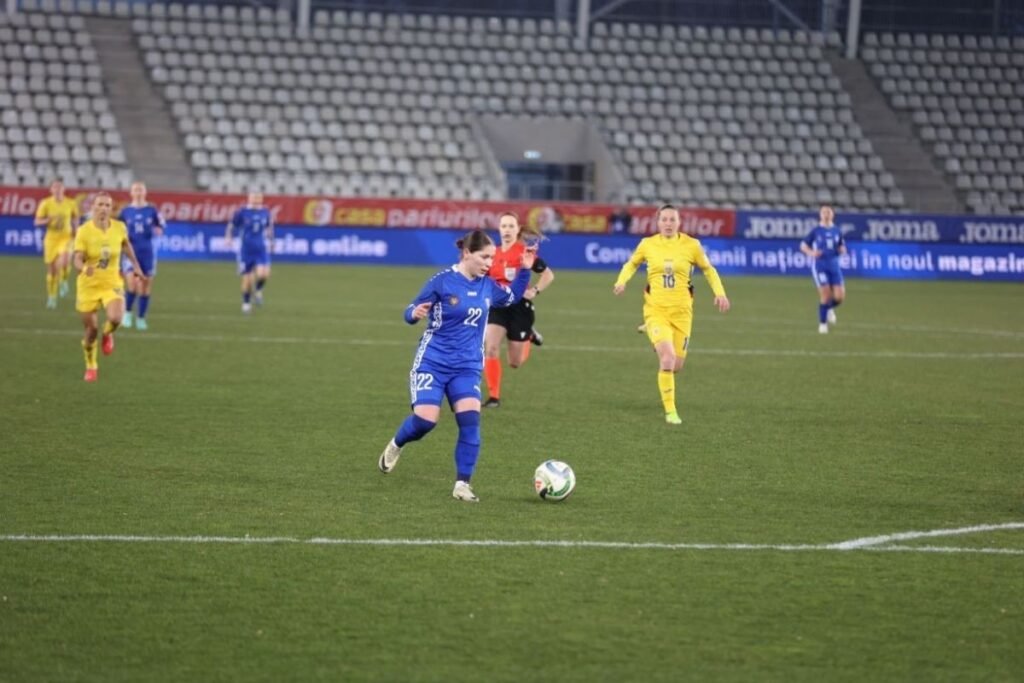 Футболистка сборной Молдовы под номером 22 ведёт мяч в матче отборочного турнира против соперниц в жёлтой форме