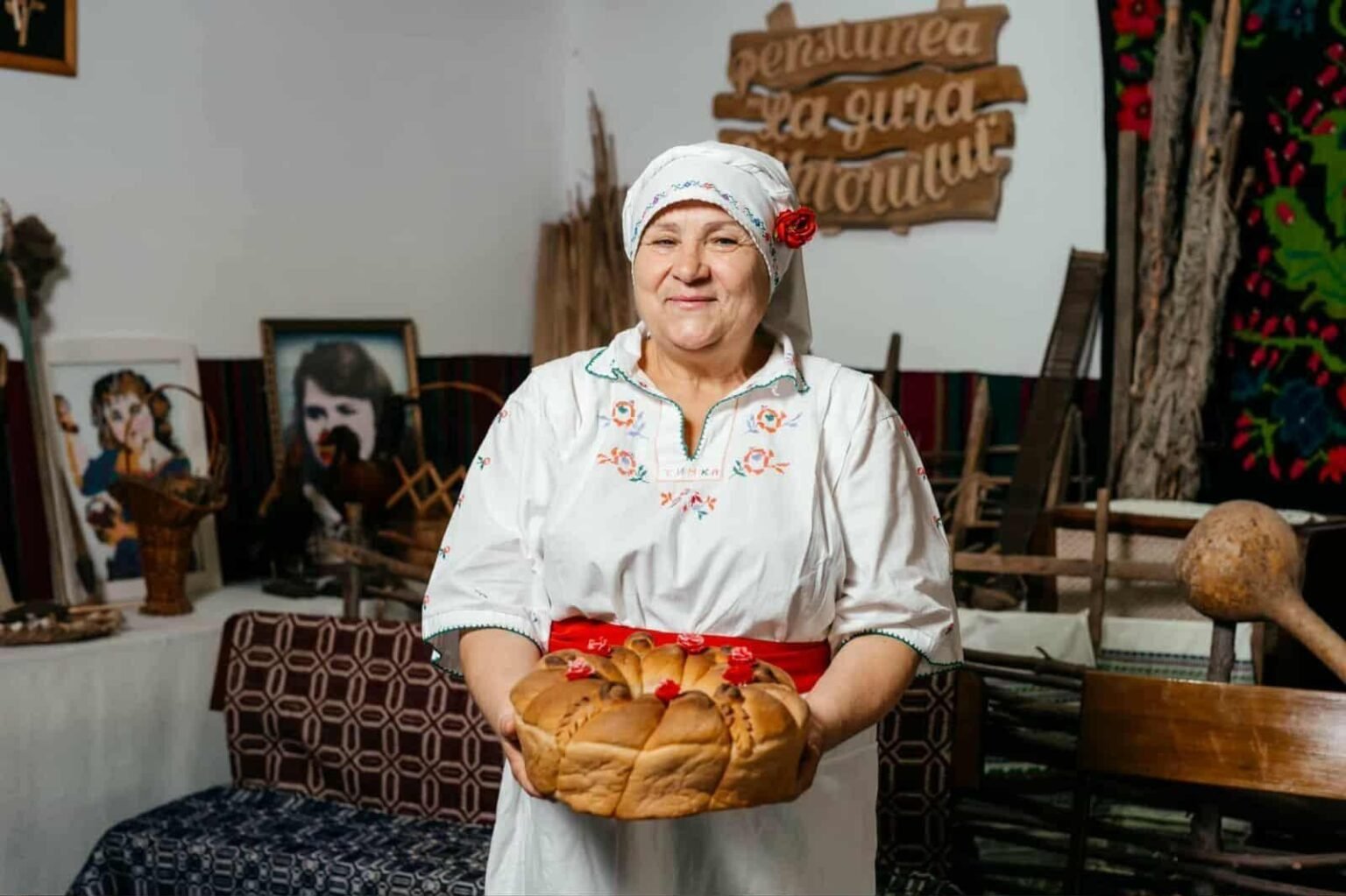 Женщина в традиционной молдавской одежде держит праздничный пасхальный хлеб в Музее хлеба в селе Вэлень