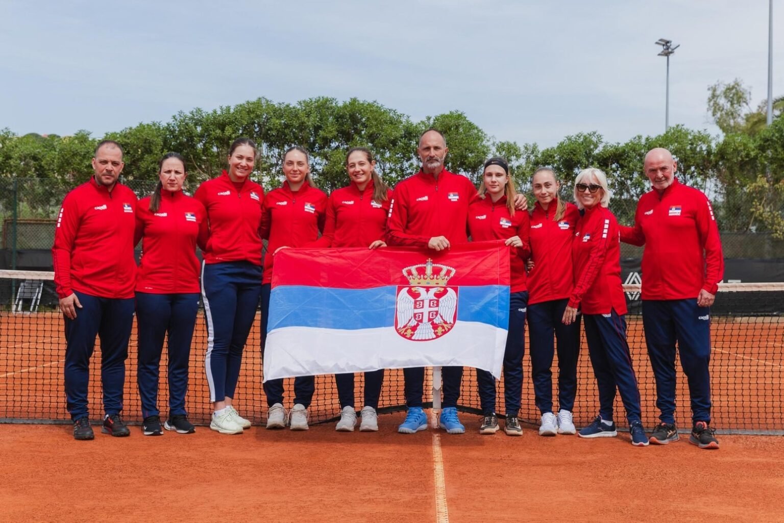 Сербские теннисистки упустили шанс вернуться в элиту Женская сборная Сербии по теннису позирует с национальным флагом на грунтовом корте перед матчем квалификации Кубка Билли Джин Кинг