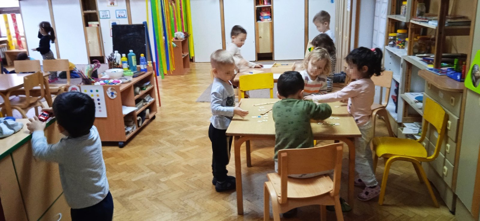 Дети играют за столами в игровой комнате детского сада