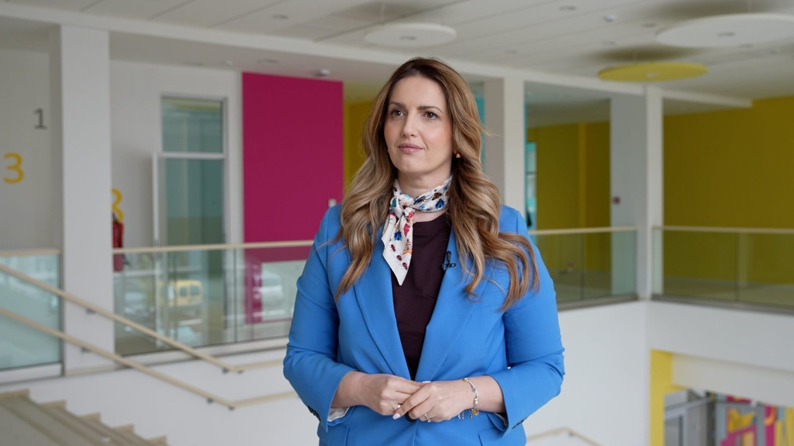 Женщина в голубом пиджаке в холле современного дошкольного учреждения