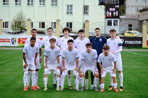 Построение молодёжного состава молдавского клуба в белой форме перед стартовым свистком на стадионе с баннером Macron — будущее команд, чья судьба зависит от лицензионных решений