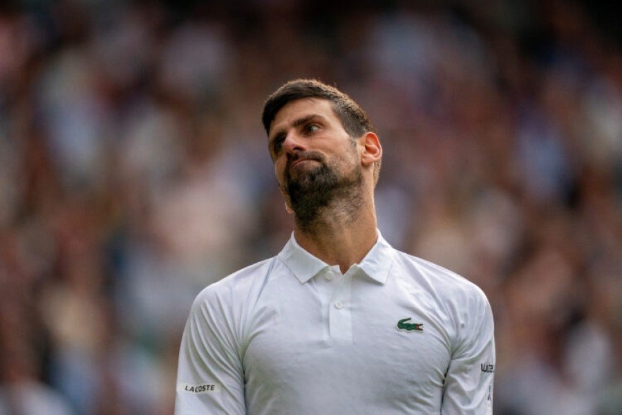 Новак Джокович в белой поло Lacoste на трибуне теннисного турнира
