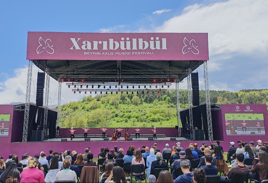 Главная сцена IX Международного музыкального фестиваля «Харыбюльбюль» с фирменным баннером Xarıbülbül на фоне карабахских холмов; зрители заполнили площадку перед открытым концертом в Шуше
